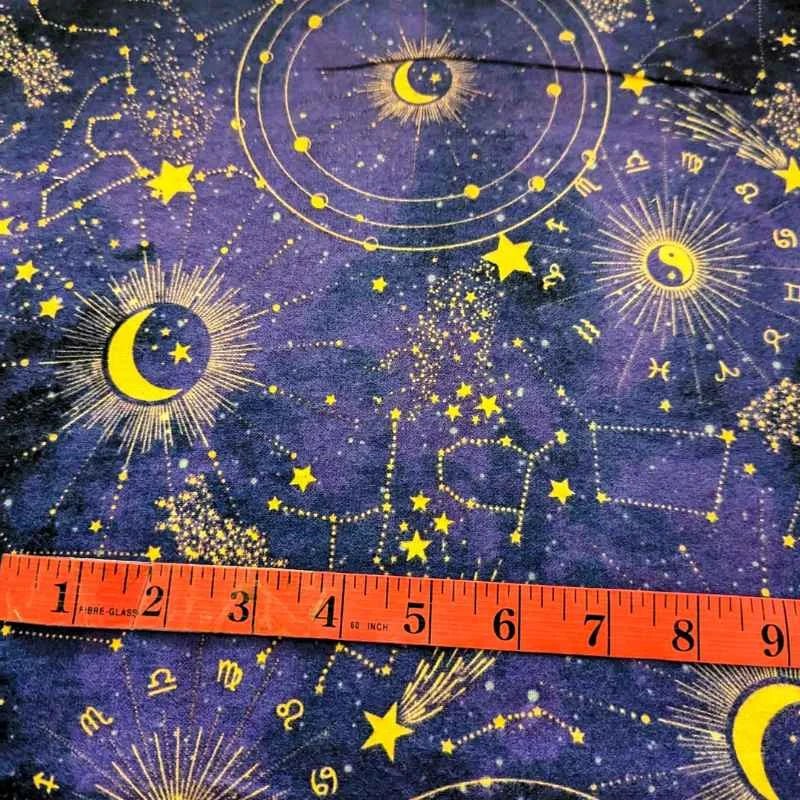 Purple cotton flannel fabric with golden zodiac constellations, stars, suns, and moons, brushed for softness, 44" wide – perfect for quilts and celestial crafts.