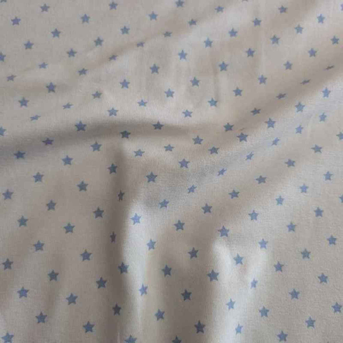 Organic cotton jersey knit fabric with blue star pattern on white background