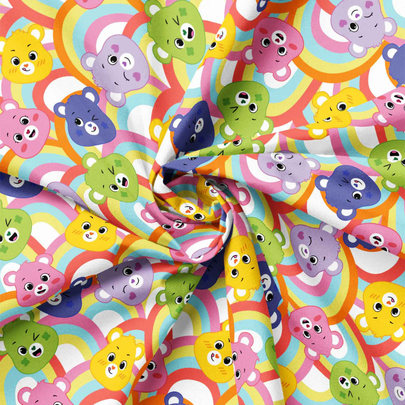 “Licensed Care Bears rainbow cotton fabric with multicolored Care Bears faces over repeating rainbow arches.”