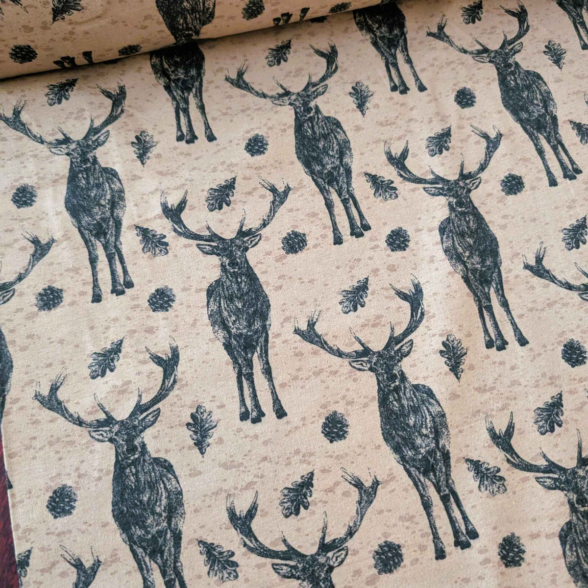 Cotton flannel fabric with stag deer, oak leaves, and pinecones on a rustic beige background, brushed for softness, Oeko-Tex certified.