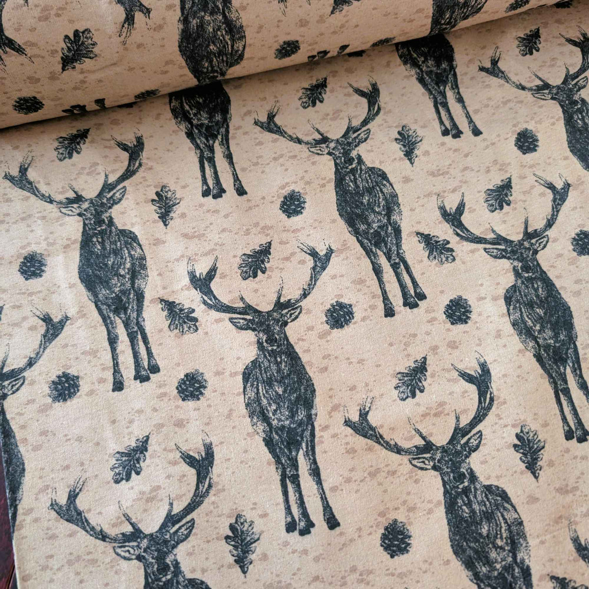 Cotton flannel fabric with stag deer, oak leaves, and pinecones on a rustic beige background, brushed for softness, Oeko-Tex certified.