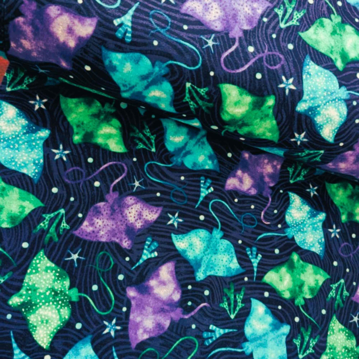 Cotton flannel fabric with colorful stingrays in blue, green, and purple on a dark ocean background with seaweed and starfish. Brushed soft, OEKO-TEX certified, 44 inches wide.
