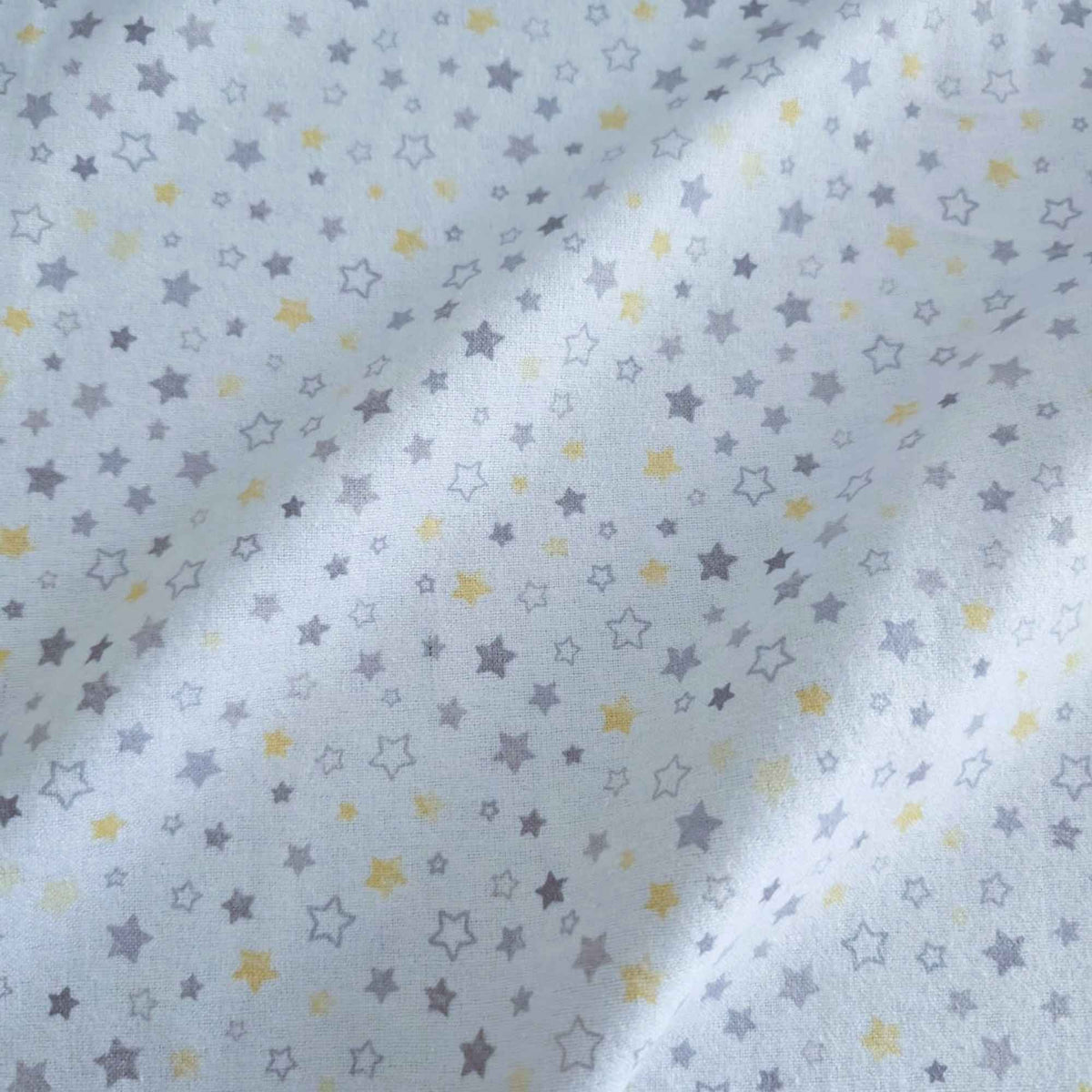 White fabric with a repeating pattern of small stars in light gray and yellow, shown with soft folds.