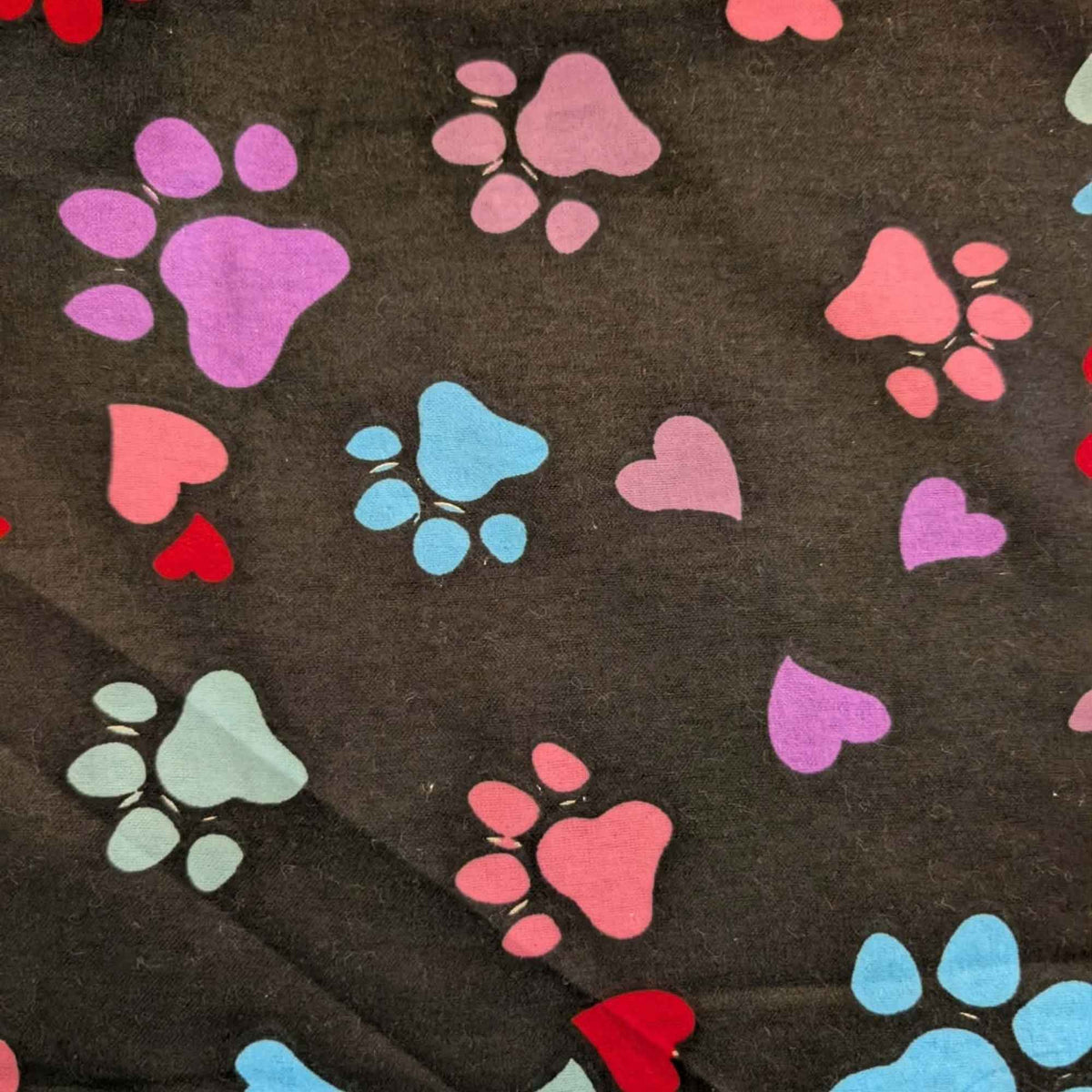 Black cotton flannel fabric with scattered paw prints and hearts in pink, purple, red, turquoise and aqua