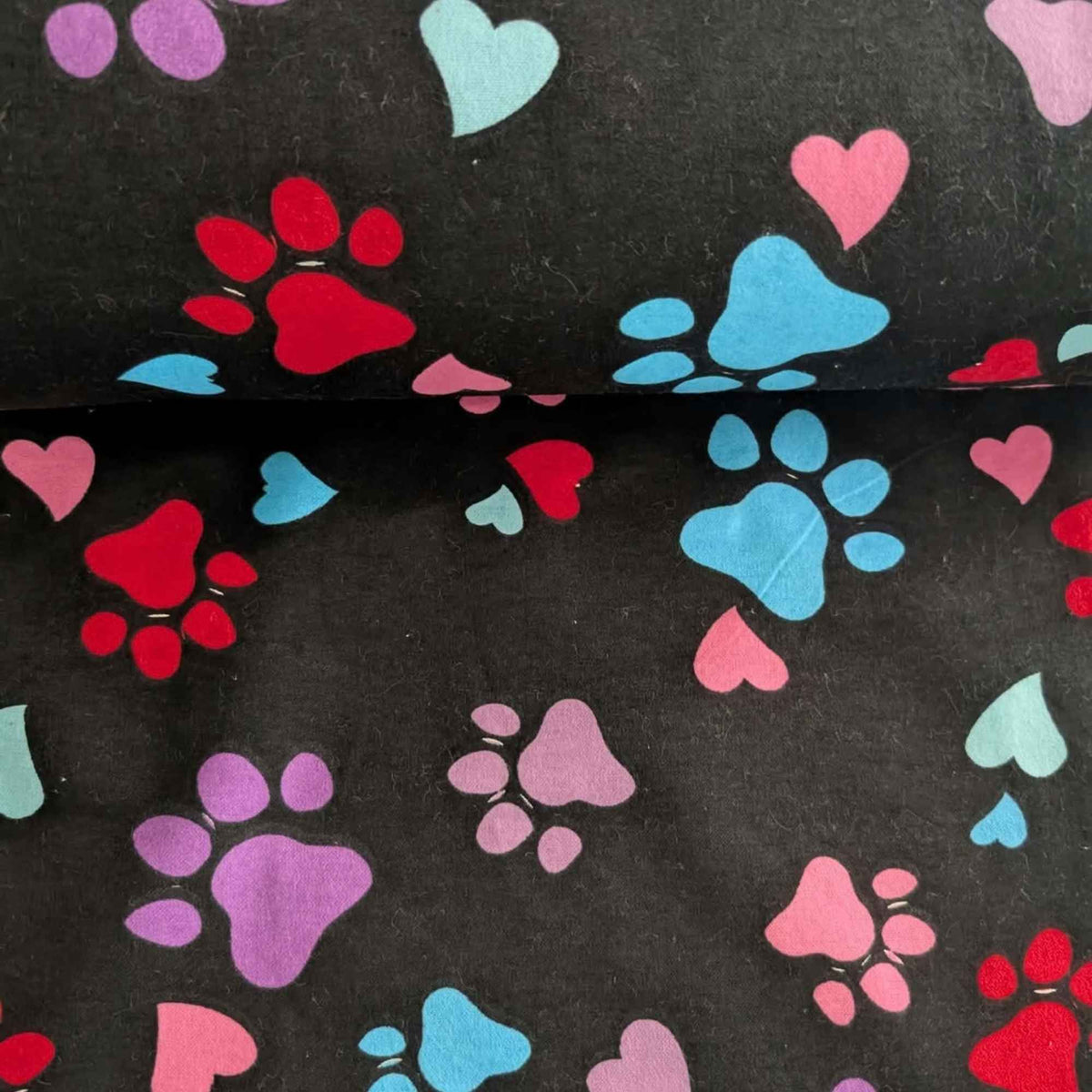 Black cotton flannel fabric with scattered paw prints and hearts in pink, purple, red, turquoise and aqua