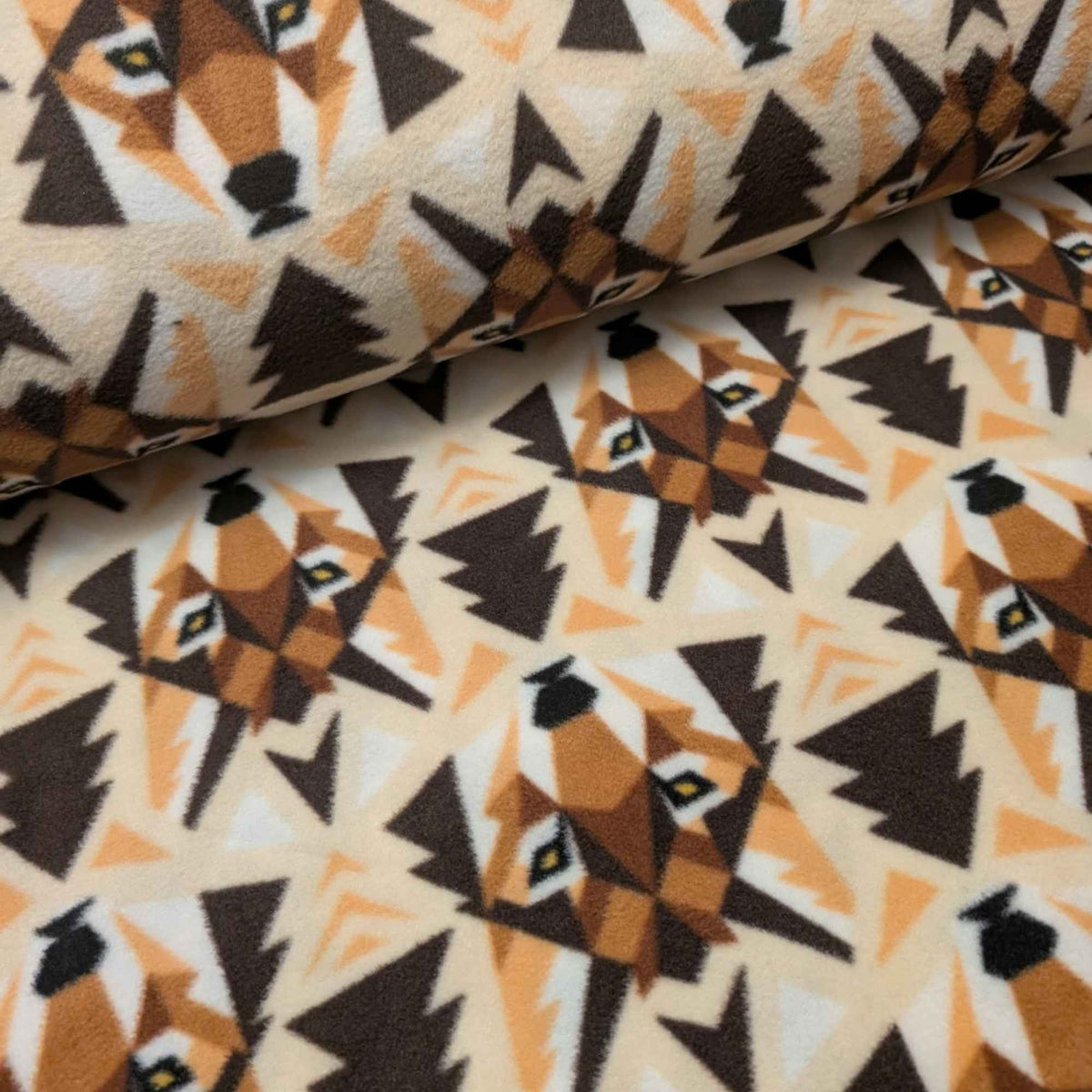 Wolf Face fleece by Camelot with geometric brown and tan wolves, dark tree silhouettes and chevrons on a cream background.