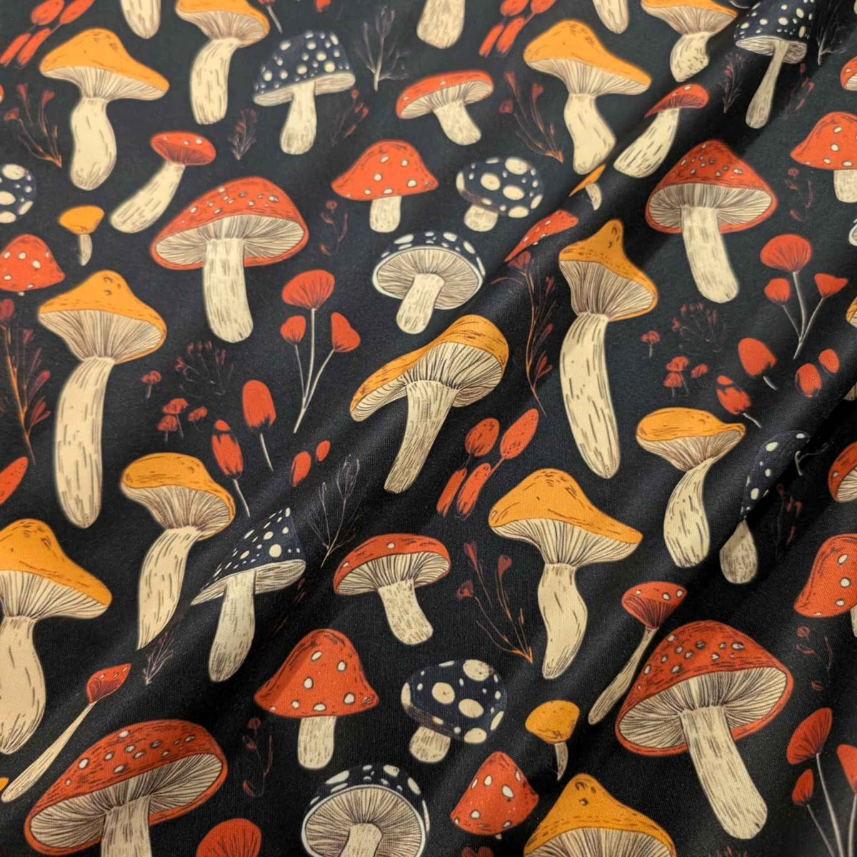 Red and golden mushroom print waterproof food safe PUL fabric on black background with botanical accents.