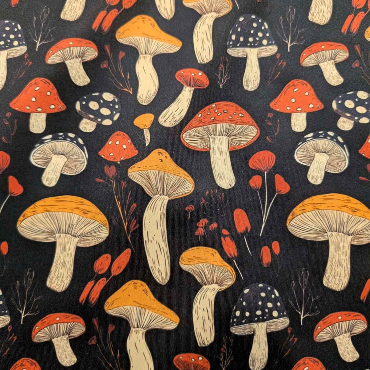 Red and golden mushroom print waterproof food safe PUL fabric on black background with botanical accents.