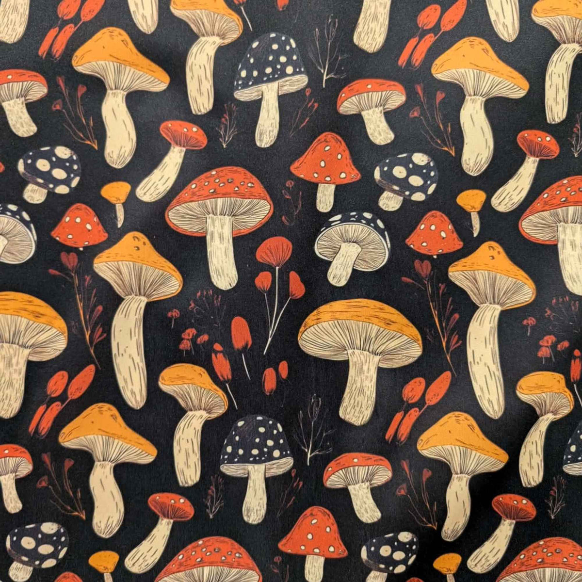 Red and golden mushroom print waterproof food safe PUL fabric on black background with botanical accents.