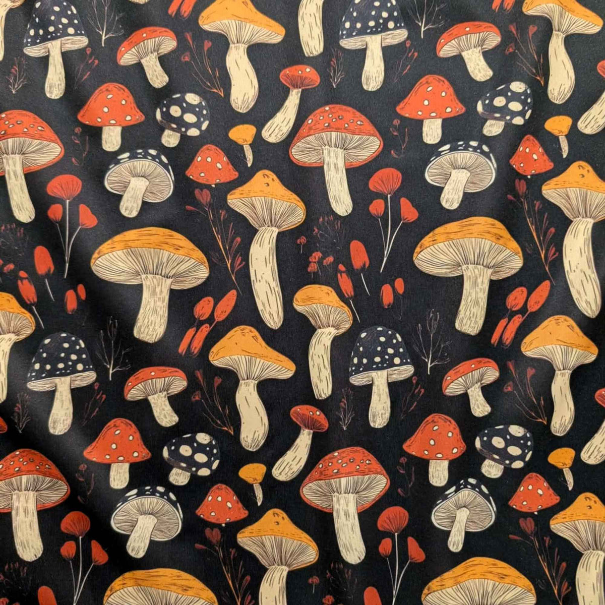 Red and golden mushroom print waterproof food safe PUL fabric on black background with botanical accents.