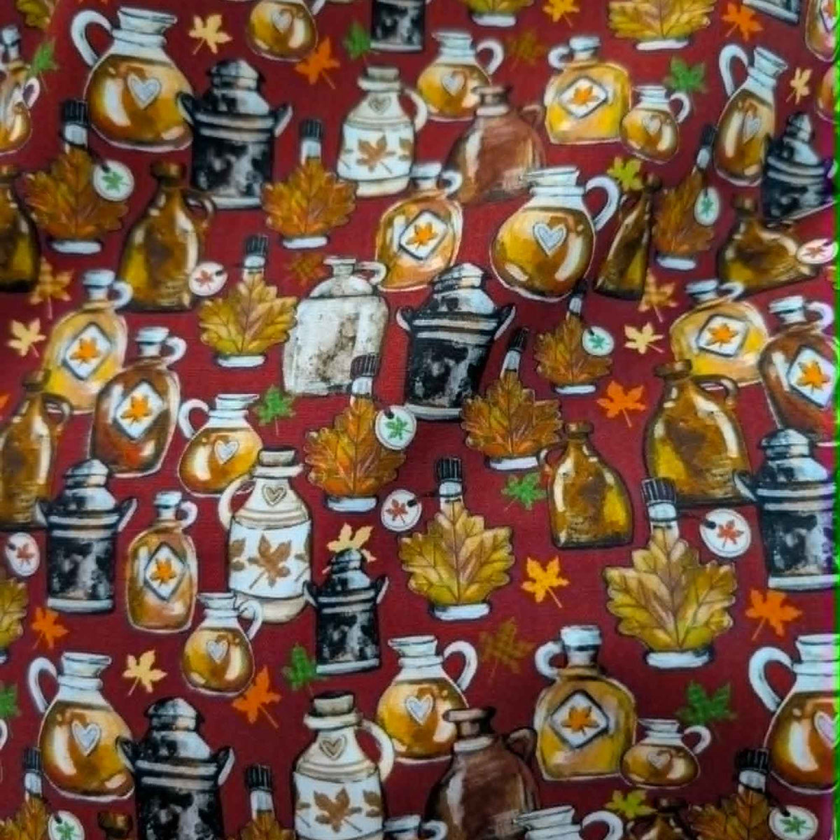 Autumn maple syrup jugs and fall leaves cotton fabric on red background with rustic harvest theme