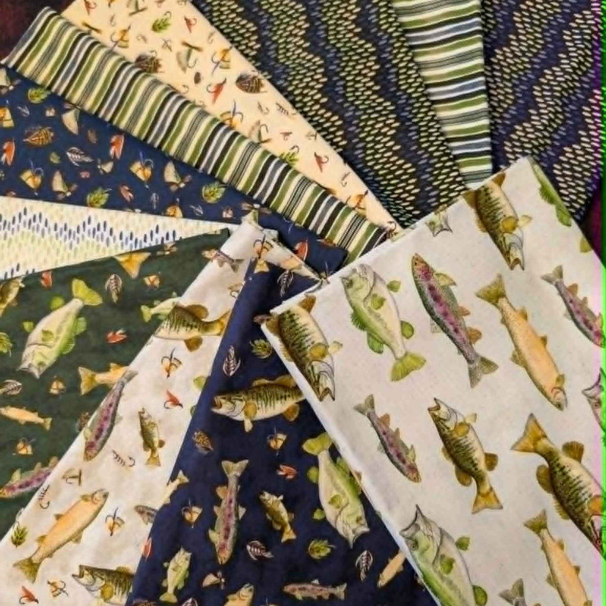 Fishful Thinking fabric bundle by Camelot Fabrics and Brett Blumenthal featuring 11 coordinating quilting cotton prints with fish, fishing lures, tackle, stripes, and rustic outdoor patterns in navy blue, green, cream, and natural tones