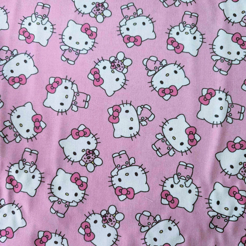 Officially licensed Hello Kitty cotton fabric by Springs Creative featuring an all-over toss of Hello Kitty holding a teddy bear on a pink background.