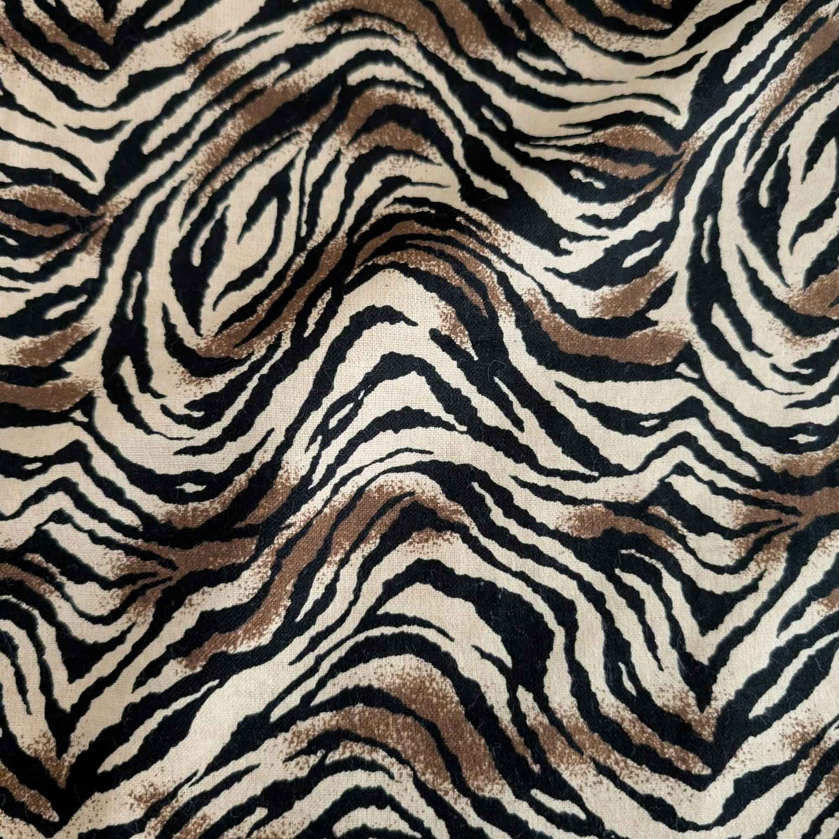 Tiger stripe cotton flannel fabric featuring wavy black stripes and brown accents on a cream background.