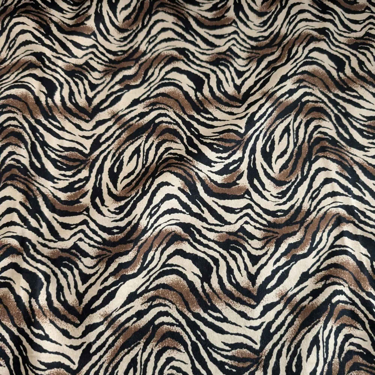 Tiger stripe cotton flannel fabric featuring wavy black stripes and brown accents on a cream background.