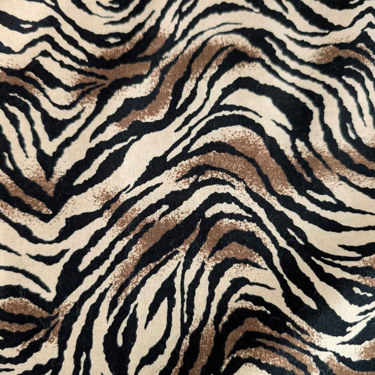Tiger stripe cotton flannel fabric featuring wavy black stripes and brown accents on a cream background.