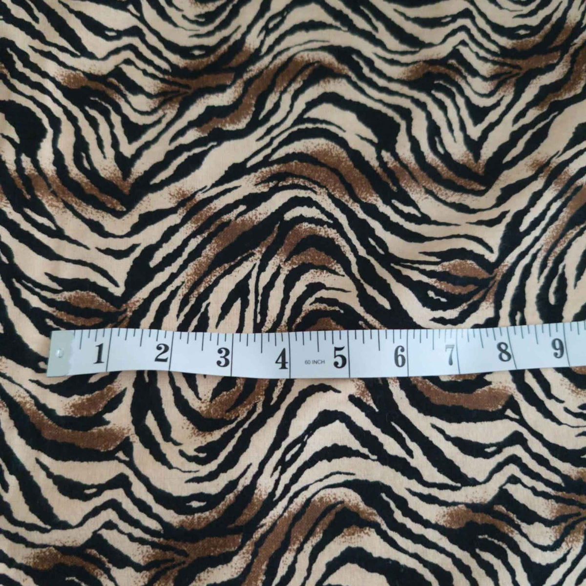 Tiger stripe cotton flannel fabric featuring wavy black stripes and brown accents on a cream background.