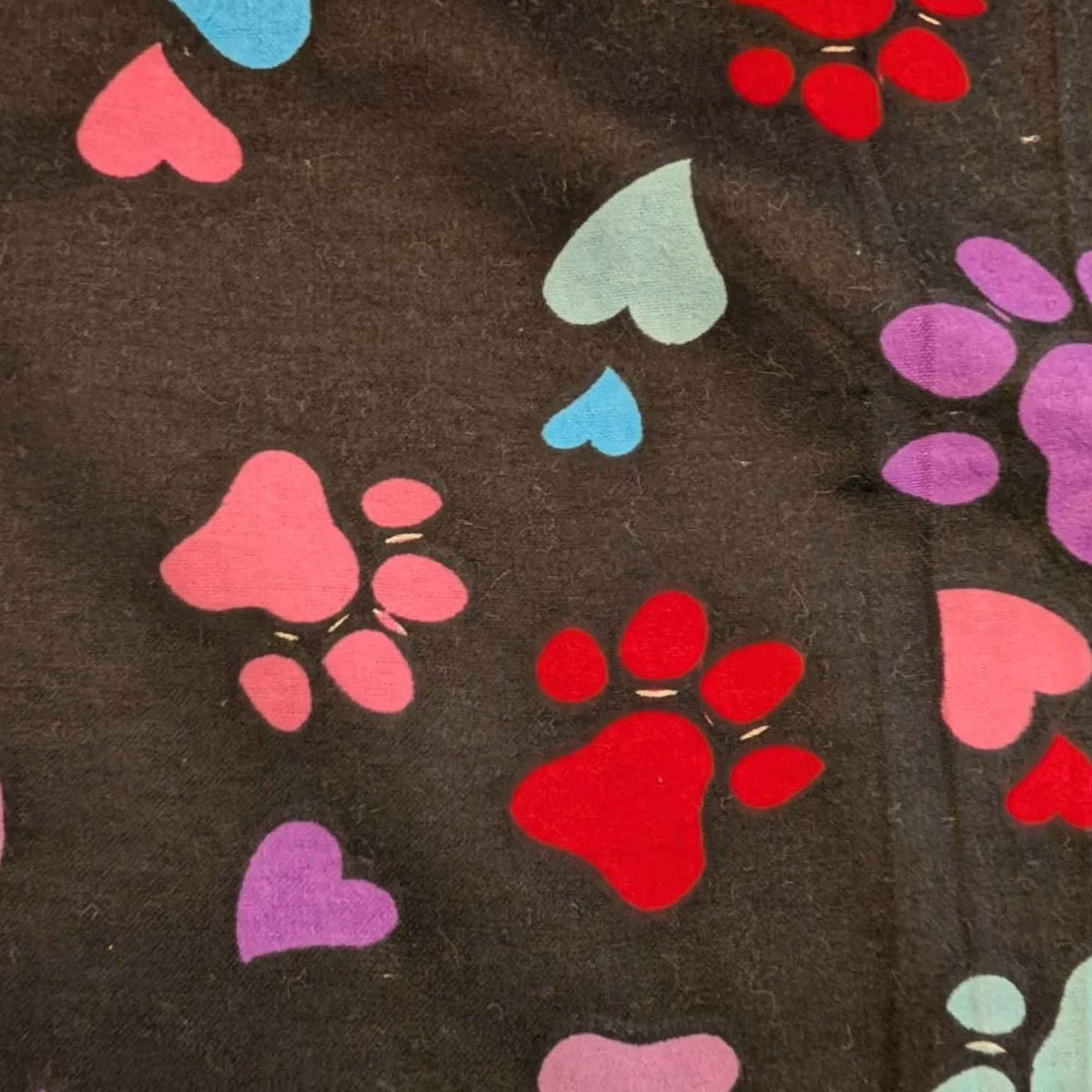 Black cotton flannel fabric with scattered paw prints and hearts in pink, purple, red, turquoise and aqua