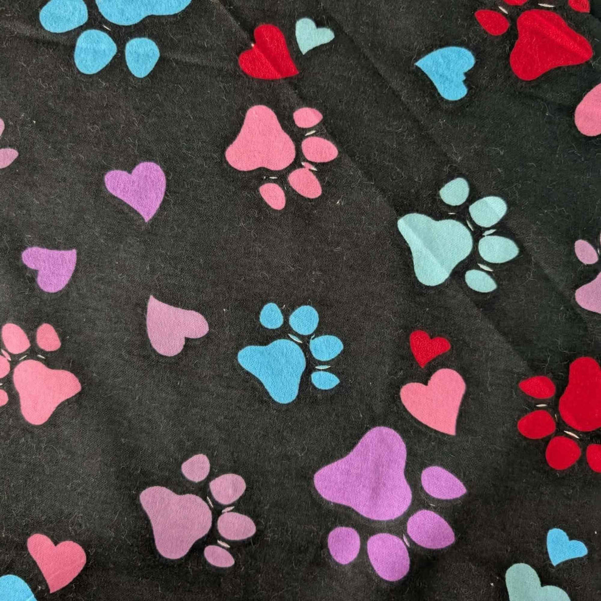 Black cotton flannel fabric with scattered paw prints and hearts in pink, purple, red, turquoise and aqua