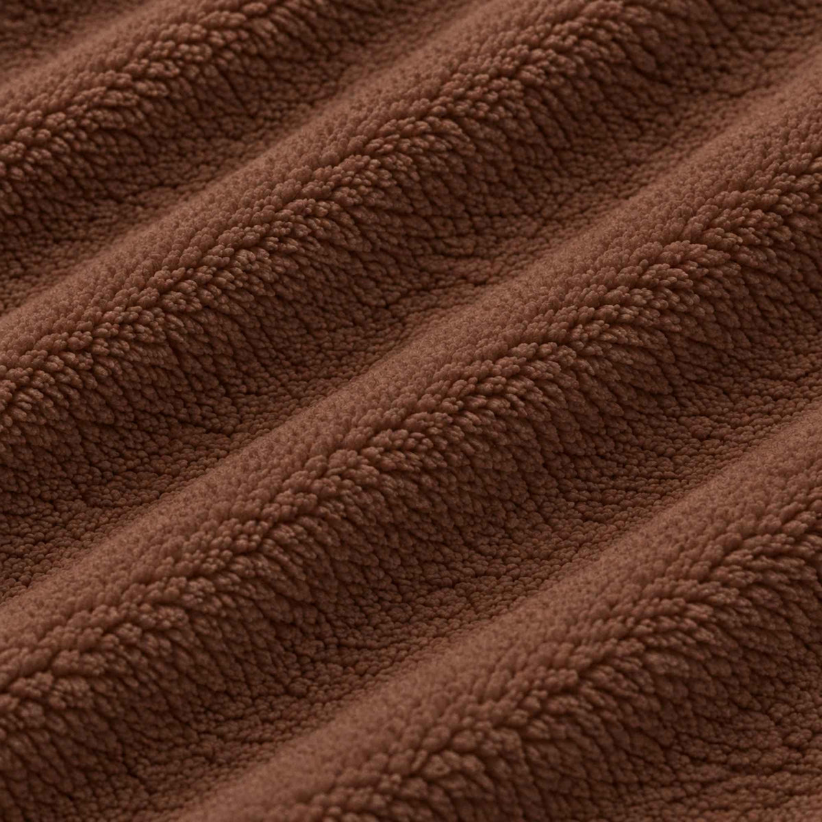 Chocolate brown anti-pill polar fleece fabric by Camelot Fabrics, close-up showing soft plush texture, dense fibers and gentle rippling folds