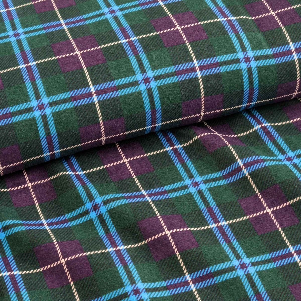 Teal green and purple tartan plaid cotton flannel fabric with bright blue crossing bands, thin cream lines and black accents.