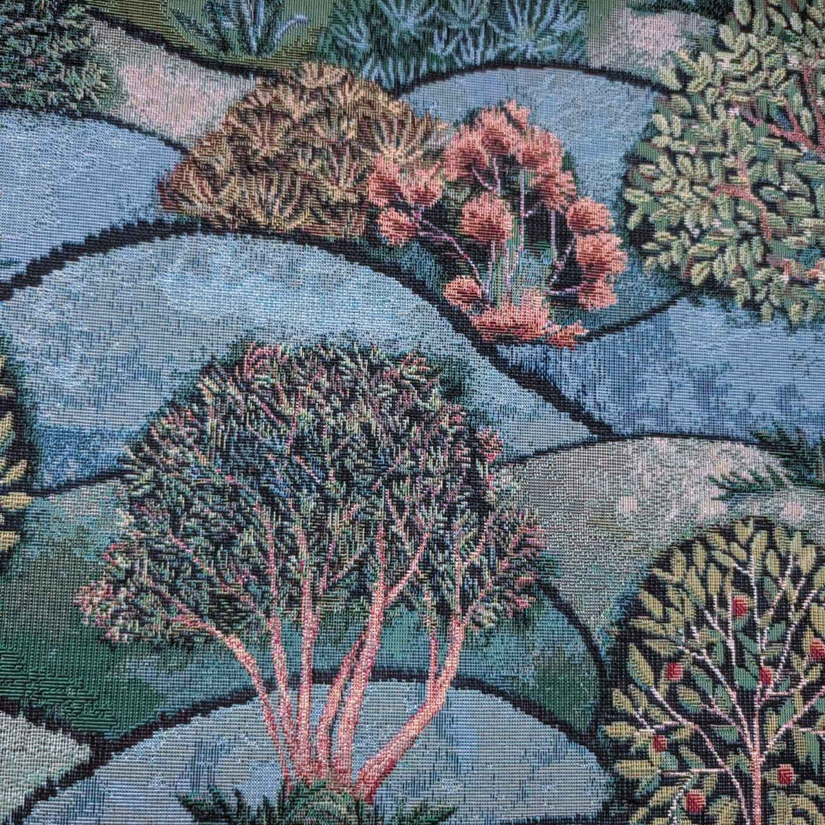 Forest Hill Woodland Trees Gobelin tapestry fabric with leafy trees, muted pink branches and rolling blue and sage green hills.