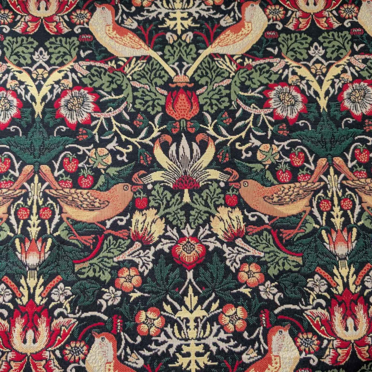 Black Gobelin tapestry fabric featuring golden birds, red strawberries, ornate flowers and scrolling green foliage.