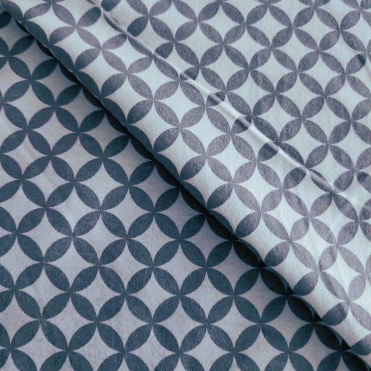 Grey interlocking rings geometric pattern on white 100% cotton flannel fabric, brushed on both sides and ideal for quilting, bedding, blankets, and sewing projects.