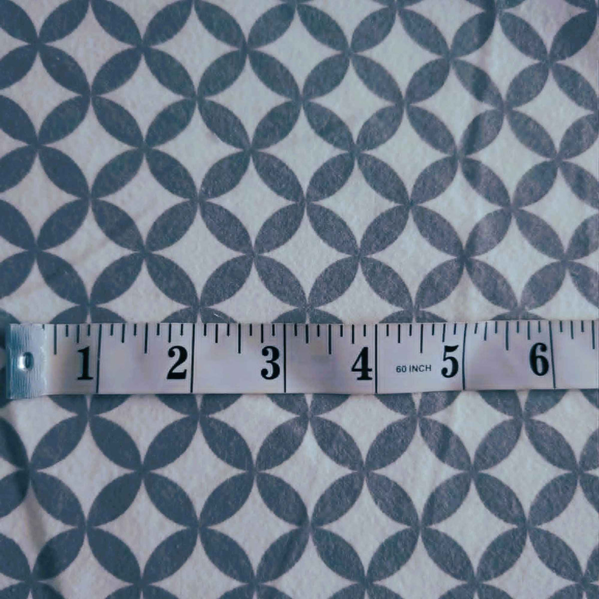 Grey interlocking rings geometric pattern on white 100% cotton flannel fabric, brushed on both sides and ideal for quilting, bedding, blankets, and sewing projects.