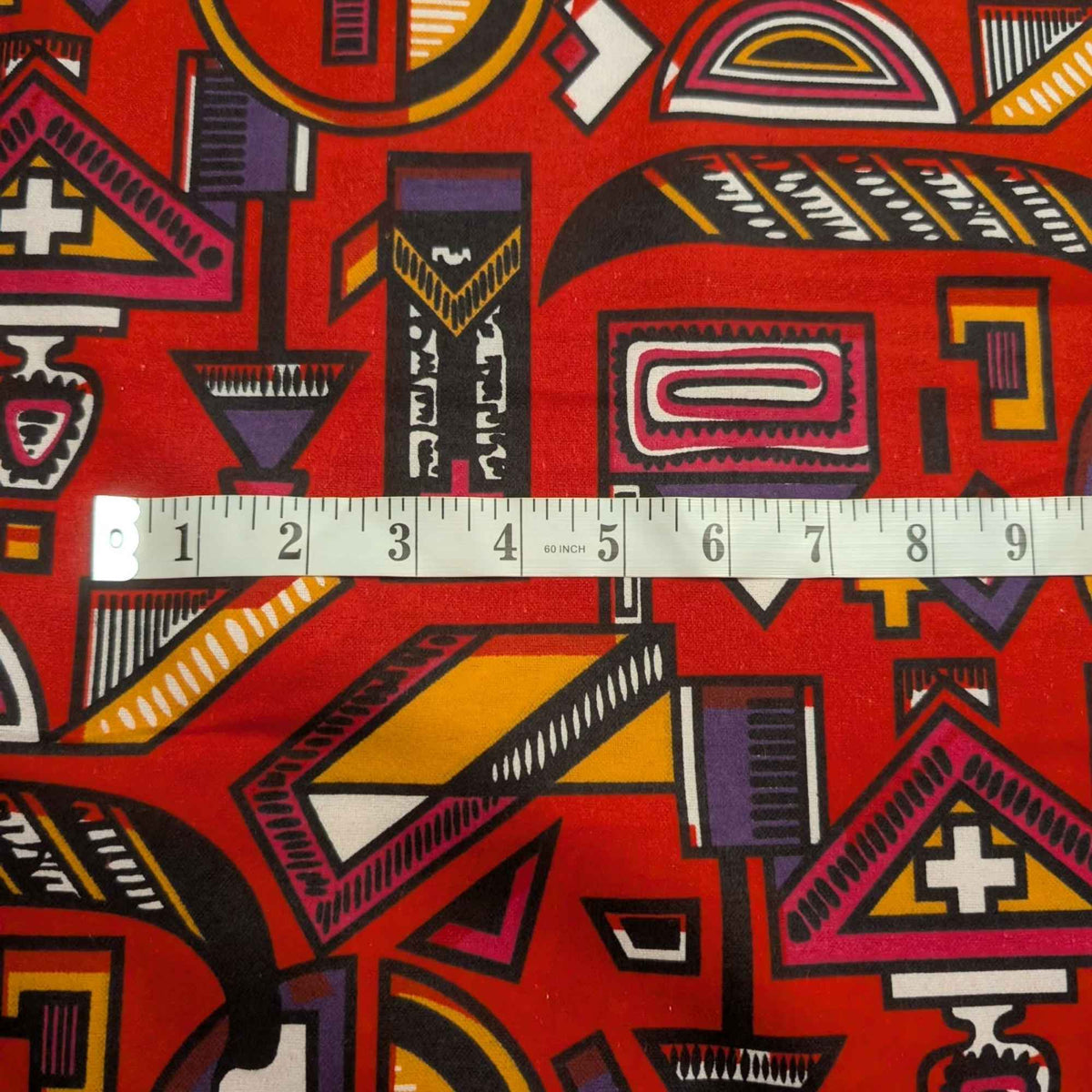 African-inspired geometric tribal double brushed flannel fabric featuring colorful abstract symbols and ethnic geometric patterns on a red background.