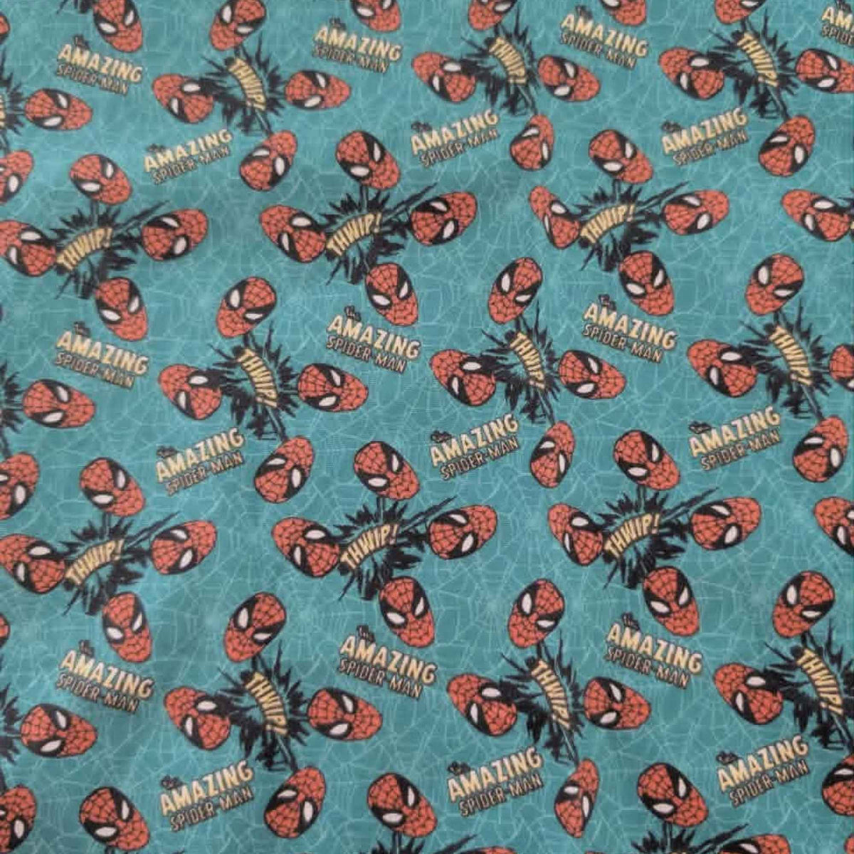 Marvel Amazing Spider-Man quilting cotton fabric by Camelot Fabrics featuring Spider-Man masks, Amazing Spider-Man logos, and comic-style Whip graphics on a turquoise web-pattern background.