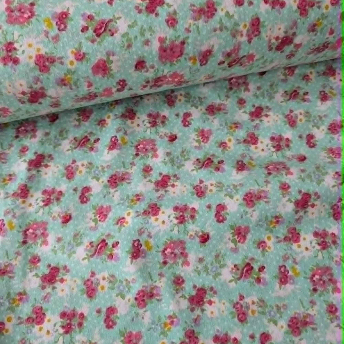 Double brushed flannel fabric featuring pink rose bouquets, delicate wildflowers, and floral sprigs on a soft mint green background.