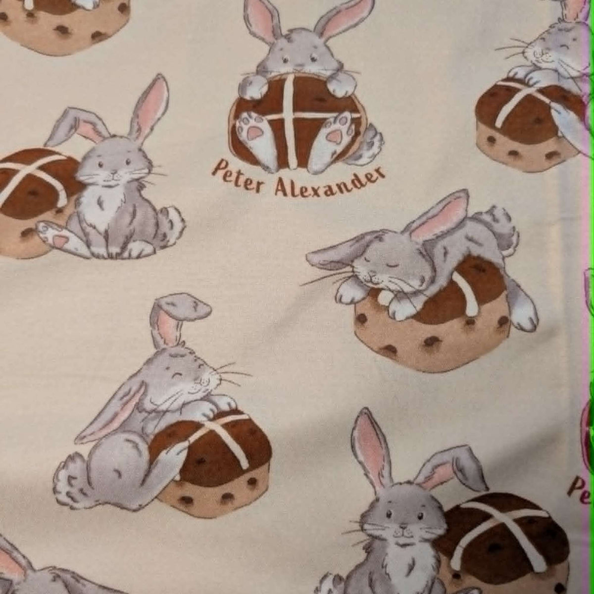 Double brushed flannel fabric featuring adorable bunny rabbits resting beside hot cross buns on a cream background.