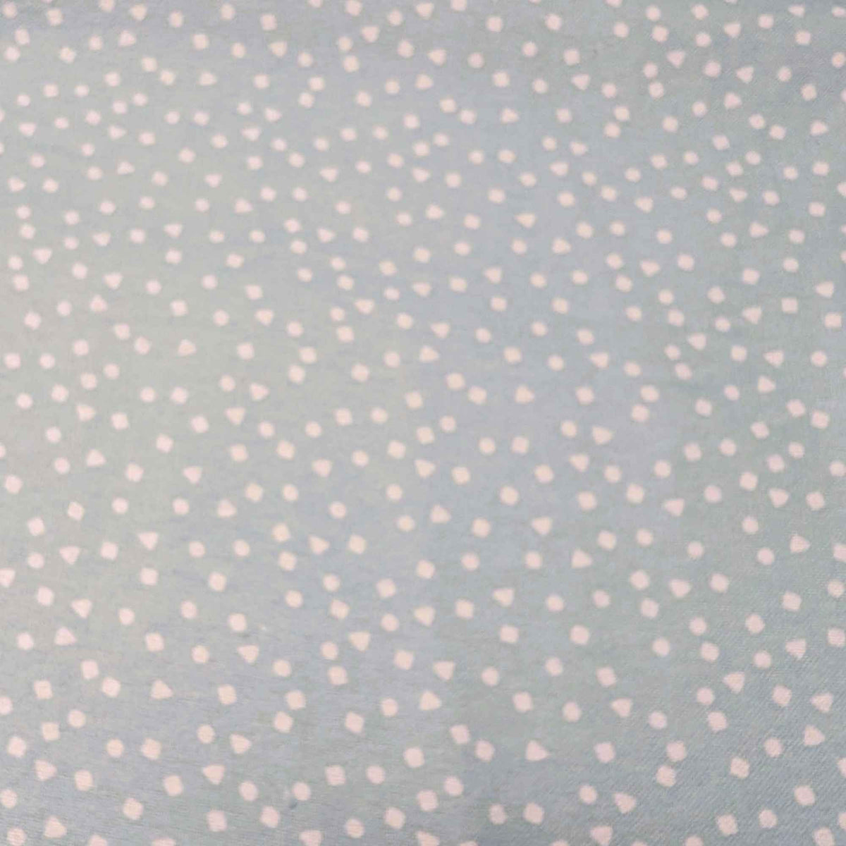 A close-up of a light blue-gray fabric with a scattered pattern of small white dots, triangles, and squares.